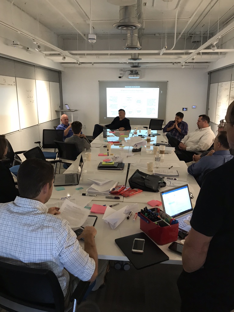 Participants around a table covered in Post-it notes and papers during an early AFWERX design workshop